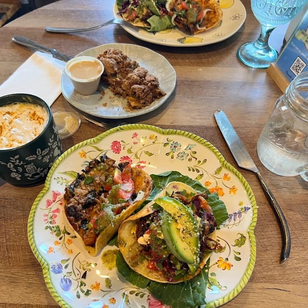 A table with healthy tacos, a crumble dessert, and a coffee mug.