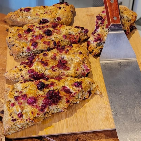 Strive Foods' berry scones with a spatula on a wooden cutting board.