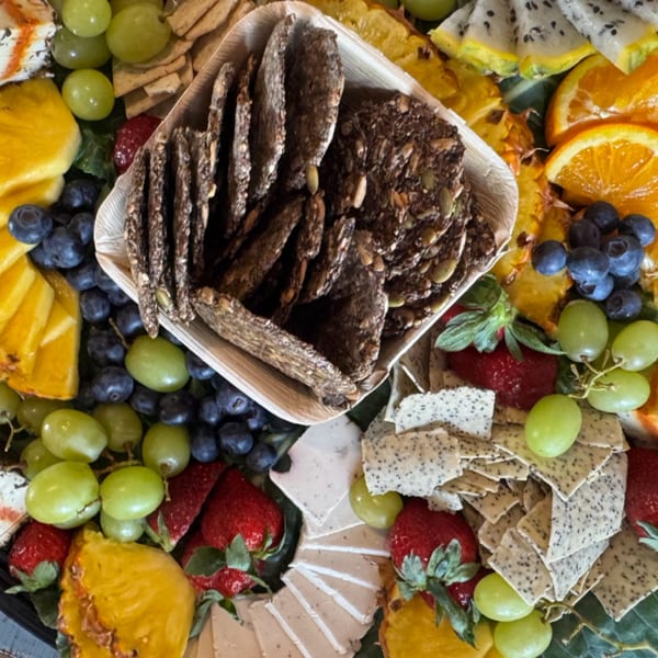 A vibrant Strive Foods charcuterie board with fruits, crackers, and healthy snacks.
