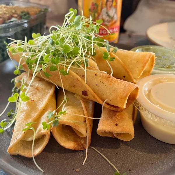 Crispy golden taquitos topped with fresh microgreens, served with two dipping sauces.
